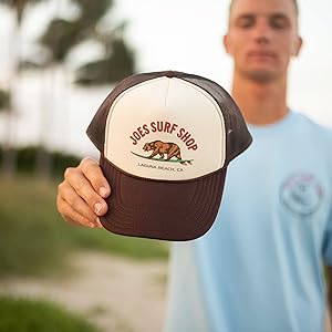 man holding a trucker hat at the beach