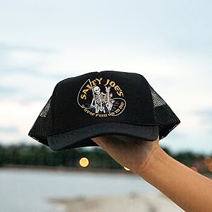 a man holding a black trucker hat